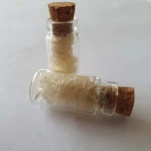 May include: Two small glass bottles with cork stoppers filled with white, flaky material.