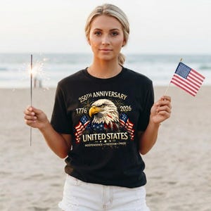 May include: Black t-shirt with a patriotic design celebrating the 250th anniversary of the United States. The graphic features an eagle, American flags, and the text "United States: Independence, Freedom, Pride."