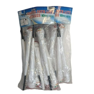 May include: A package of ten Santa Path Lite stakes. The stakes are white with a Santa Claus head design and black poles. The packaging reads "SANTA PATH LITE STAKES 10 PC. SET".