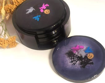Peut inclure: Ensemble de dessous de verre noirs sur le thème d'Halloween. Chaque dessous de verre présente des motifs colorés, festifs, dont des fantômes, des citrouilles et des araignées. Les dessous de verre sont ronds et sont livrés avec un support assorti.