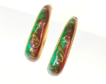 May include: A pair of gold hoop earrings with a green and pink enamel design. The enamel has a swirling pattern with gold accents.