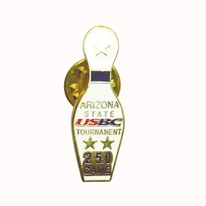 May include: A gold-coloured bowling pin lapel pin. The pin features the text "ARIZONA STATE USBC TOURNAMENT" and "250 GAME". Two gold stars are below the word "TOURNAMENT". The pin has a white body with a blue stripe.
