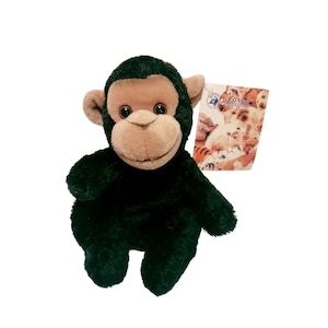 Pode incluir: Um brinquedo de pelúcia de chimpanzé com pelo preto, rosto castanho e olhos grandes e redondos. O brinquedo tem uma etiqueta anexada com o texto "LEO'S COLLECTION" e imagens de outros animais de pelúcia. O brinquedo foi projetado para se parecer com um chimpanzé realista.