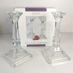May include: Two clear crystal candlesticks, each approximately 20 cm tall, with a square base and a faceted design. The box behind them reads "Tuscany Classic Series" and "8" Crystal Candlesticks".