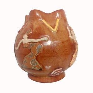May include: A brown ceramic vase with a unique, rounded shape. The vase is decorated with colorful figures and patterns, including a stylized dancer in a swirling dress.