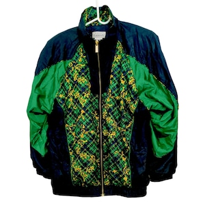 Puede incluir: Chaqueta deportiva vintage en azul marino, verde y negro. La chaqueta presenta un estampado de cuadros con detalles florales dorados en la parte delantera. Las mangas son verdes y la chaqueta tiene cierre de cremallera completo.