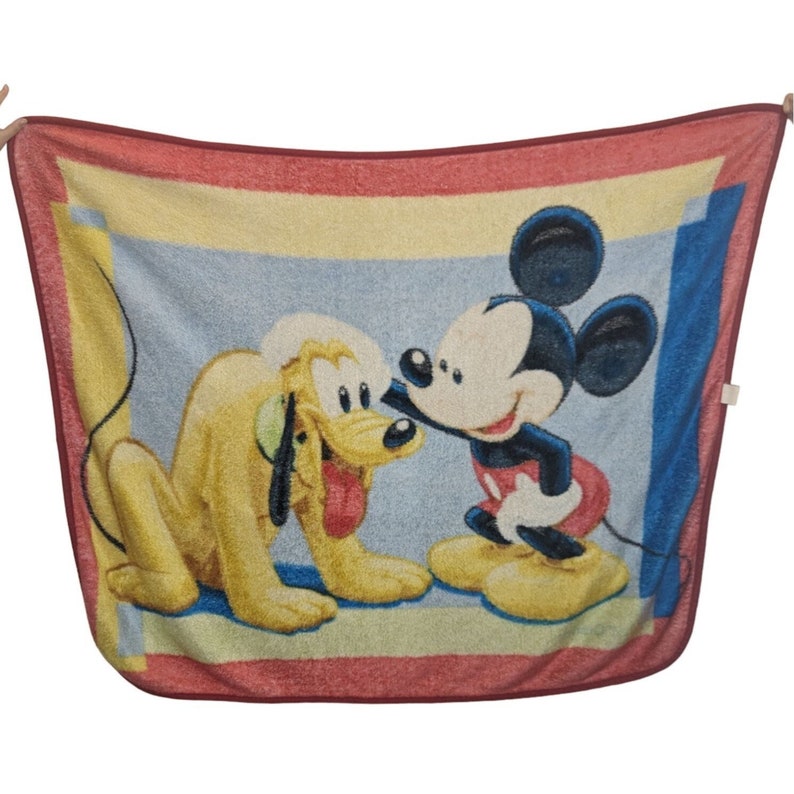 May include: A red, yellow, and blue fleece blanket with a cartoon image of Mickey Mouse and Pluto. Mickey Mouse is wearing red shorts and yellow shoes. Pluto is wearing a red collar.