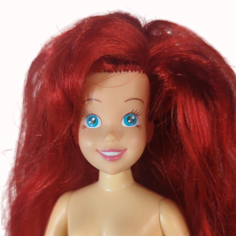 Peut inclure: Poup&eacute;e avec des cheveux roux et des yeux bleus. La poup&eacute;e a une expression souriante et n'est pas v&ecirc;tue. Les cheveux de la poup&eacute;e sont longs et fluides, et les yeux sont grands et expressifs. Personnage populaire.