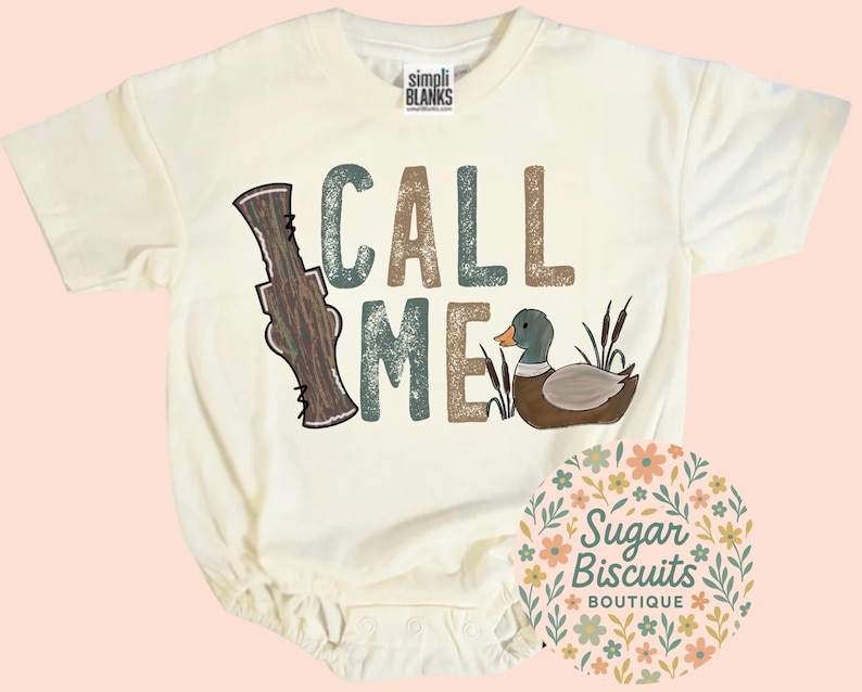 May include: Cream baby bodysuit featuring the words "CALL ME" in brown, teal, and tan lettering. A cartoon duck and a duck call graphic are also featured on the front. The bodysuit has short sleeves and snap closures.