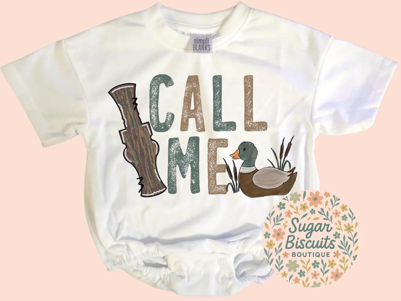 May include: White baby bodysuit with the words "CALL ME" in green, brown, and tan. A cartoon duck and duck call are featured in the design. The Sugar Biscuits Boutique logo is in the lower right corner.