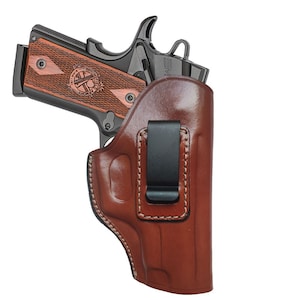 May include: A brown leather holster with a black clip for a handgun. The holster has a stitched design and is made of high-quality leather.