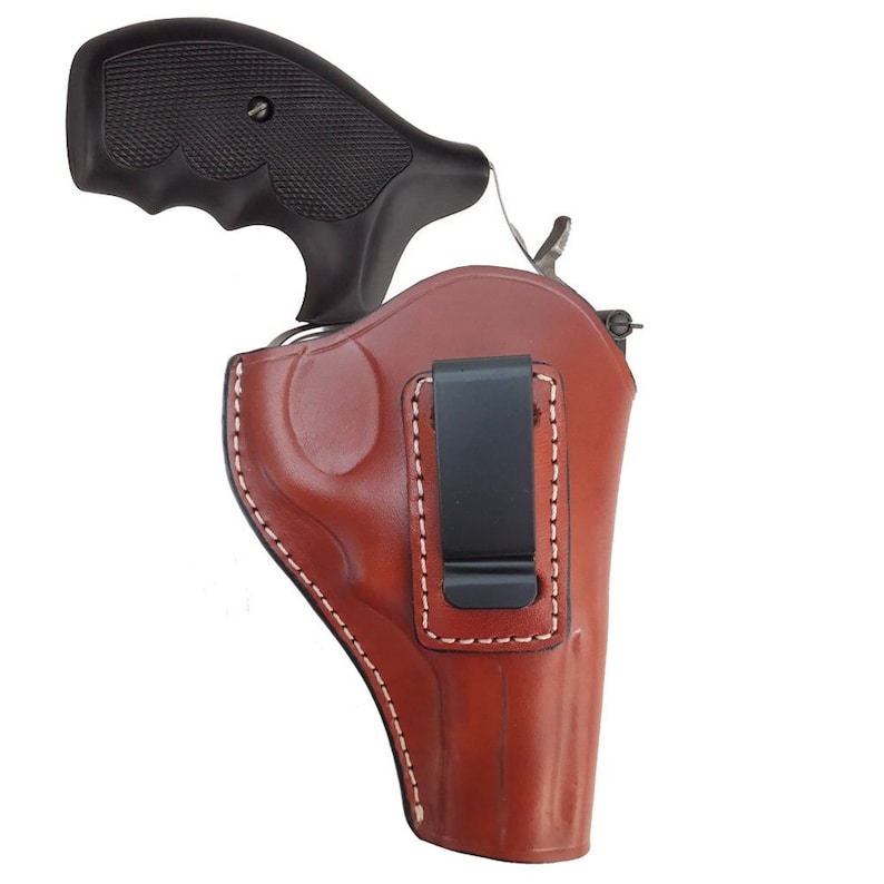 Puede incluir: Una funda de cuero marr&oacute;n con un clip negro para una pistola. La funda tiene un detalle de costura blanca.