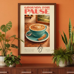 May include: A framed poster with the words "GROUNDS FOR PAUSE" in red letters. The poster features a teal cup of coffee with latte art, a saucer, and a biscotti. The words "BEAUTIFULLY UNEXPECTED" are also on the poster.