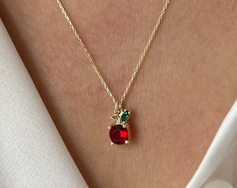 May include: A gold chain necklace with a red and green apple pendant. The apple is made of red and green gemstones.