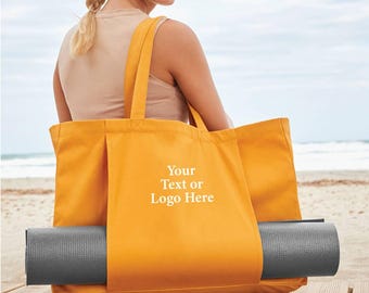 May include: Mustard yellow tote bag with a rolled-up gray yoga mat. The bag has long handles and the text "Your Text or Logo Here" printed on the front. The bag is made of a sturdy fabric and is designed to carry yoga equipment.