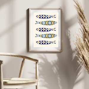 May include: A framed print of five colorful fish with a blue and white tiled pattern. The fish are arranged vertically in a row, with the tails pointing to the right. The background is a light cream color.