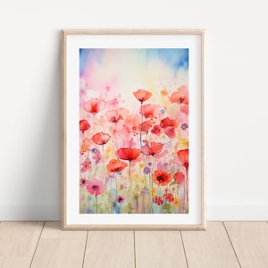 Op de afbeelding: Aquarel schilderij van rode klaprozen en andere wilde bloemen in een veld. Het kunstwerk heeft een zachte, dromerige kwaliteit met een lichtroze, blauwe en gele achtergrond. De schildering is ingelijst in een licht houten frame.