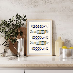 May include: A framed print of five blue, yellow, and white fish with geometric patterns. The fish are arranged vertically on a cream background.
