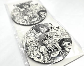 Op de afbeelding: Twee ronde zwarte en witte onderzetters met een ontwerp van meerdere anime-achtige vrouwelijke gezichten. De onderzetters bevinden zich op een witte achtergrond.