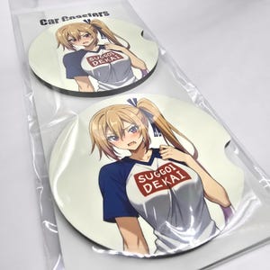 Może przedstawiać: Dwa okrągłe podkładki do samochodu z postacią anime o długich blond włosach, ubraną w białą koszulkę z czerwonym logo "Suggoi Dekai" i niebiesko-białą koszulkę baseballową.