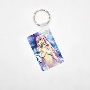 May include: A rectangular keyring featuring an anime character with long pink hair and red horns. The character is set against a blue and white background. The keyring has a silver metal ring attached.