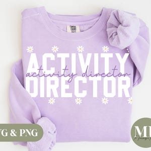 May include: A lavender sweatshirt with the text "ACTIVITY DIRECTOR" in white with a daisy pattern around the text.