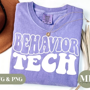 May include: Purple t-shirt with the text "Behavior Tech" in white retro-style lettering. The shirt is made of a soft, comfortable material and has a distressed look.