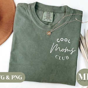 May include: A green t-shirt with the text "COOL MOMS CLUB" in white lettering. The shirt is folded and laid flat on a white surface.