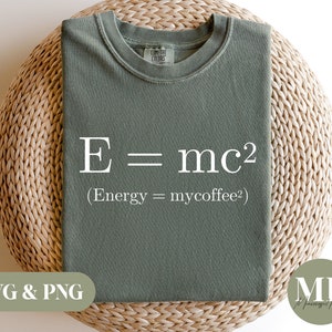May include: A green t-shirt with the equation "E = mc2" printed on it in white. The text below the equation reads "(Energy = mycoffee?)"