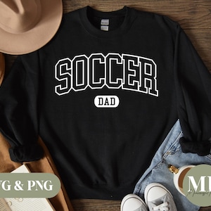 Puede incluir: Sudadera negra con texto blanco que dice "SOCCER DAD" en una fuente de estilo universitario.