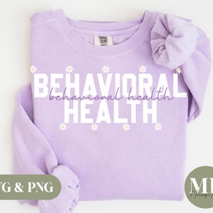 May include: A lavender sweatshirt with the text "BEHAVIORAL HEALTH" in white letters with a daisy pattern. The text "behavioral health" is in a smaller font and is below the main text.