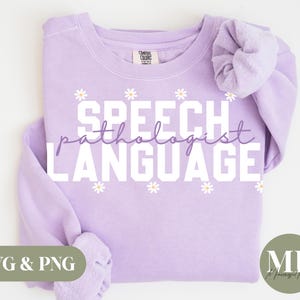 Puede incluir: Sudadera morada con el texto "Speech Pathologist Language" en letras blancas con pequeñas flores blancas de margarita alrededor del texto.