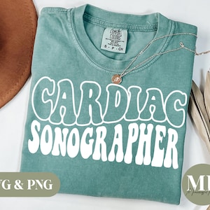 Può includere: Una maglietta blu turchese con il testo "Cardiac Sonographer" in lettere retrò bianche. La maglietta è realizzata in un materiale morbido e confortevole, perfetta per l'uso quotidiano.