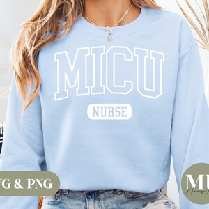 May include: A light blue sweatshirt with the text "MICU NURSE" in white block letters. The sweatshirt is a crew neck style and has a soft, comfortable appearance. The design is simple and clean, perfect for medical professionals.