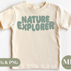 Op de afbeelding: Crèmekleurig T-shirt met de tekst "NATURE EXPLORER" in een afgerond, teal lettertype. Het shirt met korte mouwen is geschikt voor kinderen. De afbeelding bevat ook de tekst "SVG & PNG" en een cirkelvormig logo.