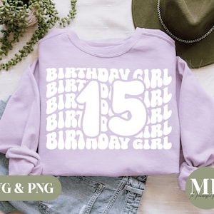 以下が含まれることがあります： ラベンダー色のスウェットシャツに、白いグラフィックデザインで「Birthday Girl」と「15」という数字がレトロな大きなフォントで書かれています。