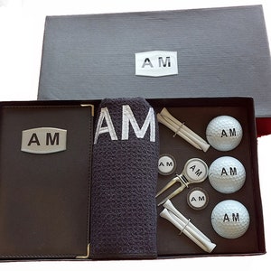 Pacote de presente de golfe personalizado com porta-score, toalha, 3 bolas, reparador de campo, 2 marcadores de bola e 6 tees lisos.