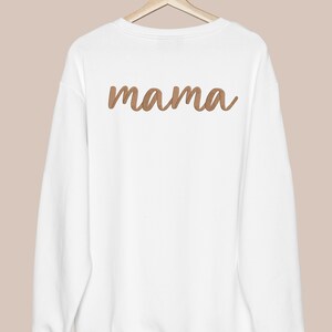 K&ouml;nnte beinhalten: Wei&szlig;er Pullover mit einem braunen gestickten "mama" auf der R&uuml;ckseite.