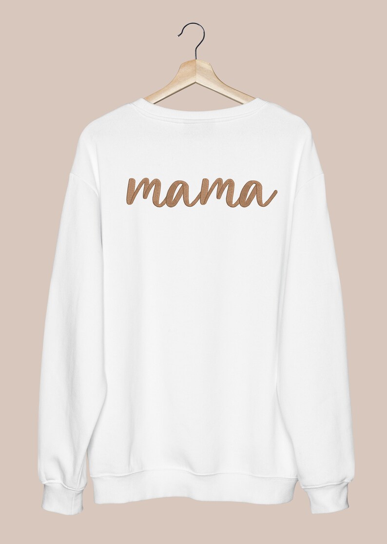 K&ouml;nnte beinhalten: Wei&szlig;er Pullover mit einem braunen gestickten "mama" auf der R&uuml;ckseite.