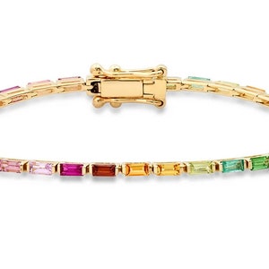 Könnte beinhalten: Goldenes Armband mit einem Regenbogen aus rechteckigen Edelsteinen. Das Armband verfügt über einen sicheren Verschluss und ein filigranes Design, das ein Farbspektrum aus Rot, Orange, Gelb, Grün, Blau und Lila zeigt. Ein lebendiges Schmuckstück.