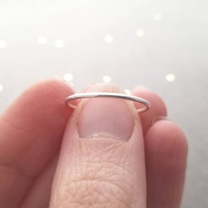 Puede incluir: Un fino anillo de plata usado en un dedo.