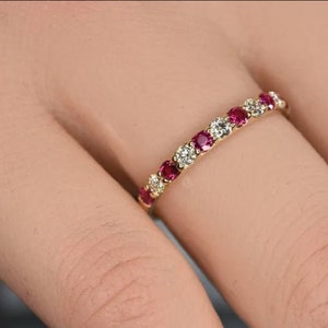 May include: A delicate gold band ring with alternating red rubies and white diamonds.