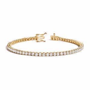 May include: A gold tennis bracelet with a row of small round diamonds.