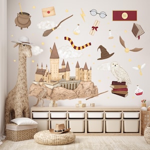 Può includere: Un set di adesivi murali a tema Harry Potter con un castello di Hogwarts, un boccino d'oro, un cappello da mago, un gufo delle nevi, una bacchetta magica, una boccetta di pozione, un libro, una lettera, un fulmine e una giraffa. Gli adesivi sono su una parete bianca sopra uno scaffale in legno con contenitori di stoccaggio bianchi.