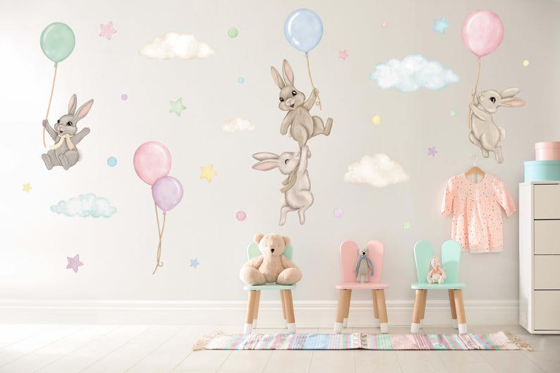 K&ouml;nnte beinhalten: Ein Wandaufkleber-Set f&uuml;r Kinderzimmer mit Hasen, die Ballons, Wolken und Sterne halten. Die Aufkleber sind in Pastellfarben gehalten und perfekt f&uuml;r ein Babyzimmer.