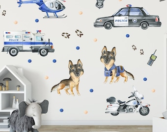 May include: A set of wall decals featuring a police car, a police truck, a police helicopter, a police motorcycle, two German Shepherd dogs wearing police vests, a police badge, a police radio, and paw prints. The decals are on a white wall with blue and peach polka dots.