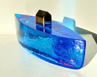 May include: A blue glass sculpture of a boat with a gold house on top. The sculpture is signed "B. Vallion."