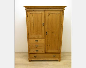 Pode incluir: Um guarda-roupa alto de madeira castanha clara com duas portas e quatro gavetas. O guarda-roupa tem um design clássico com entalhes decorativos nos cantos superiores. As portas e gavetas têm puxadores simples de cor escura.