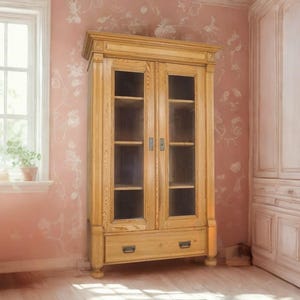 Könnte beinhalten: Ein helles Holzschrank mit Glastüren und Regalen. Der Schrank hat eine Schublade unten und steht vor einer rosa Tapete mit Blumenmuster. Der Raum hat ein Fenster und weitere passende Schränke.