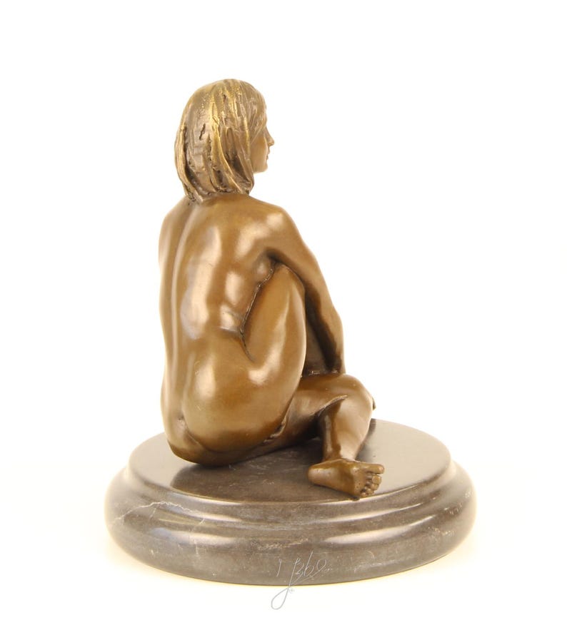 May include: Bronze sculpture of a seated figure with short hair, positioned with their back to the viewer. The figure is on a round, dark gray marble base. The sculpture has a smooth, polished finish and is set against a white background.